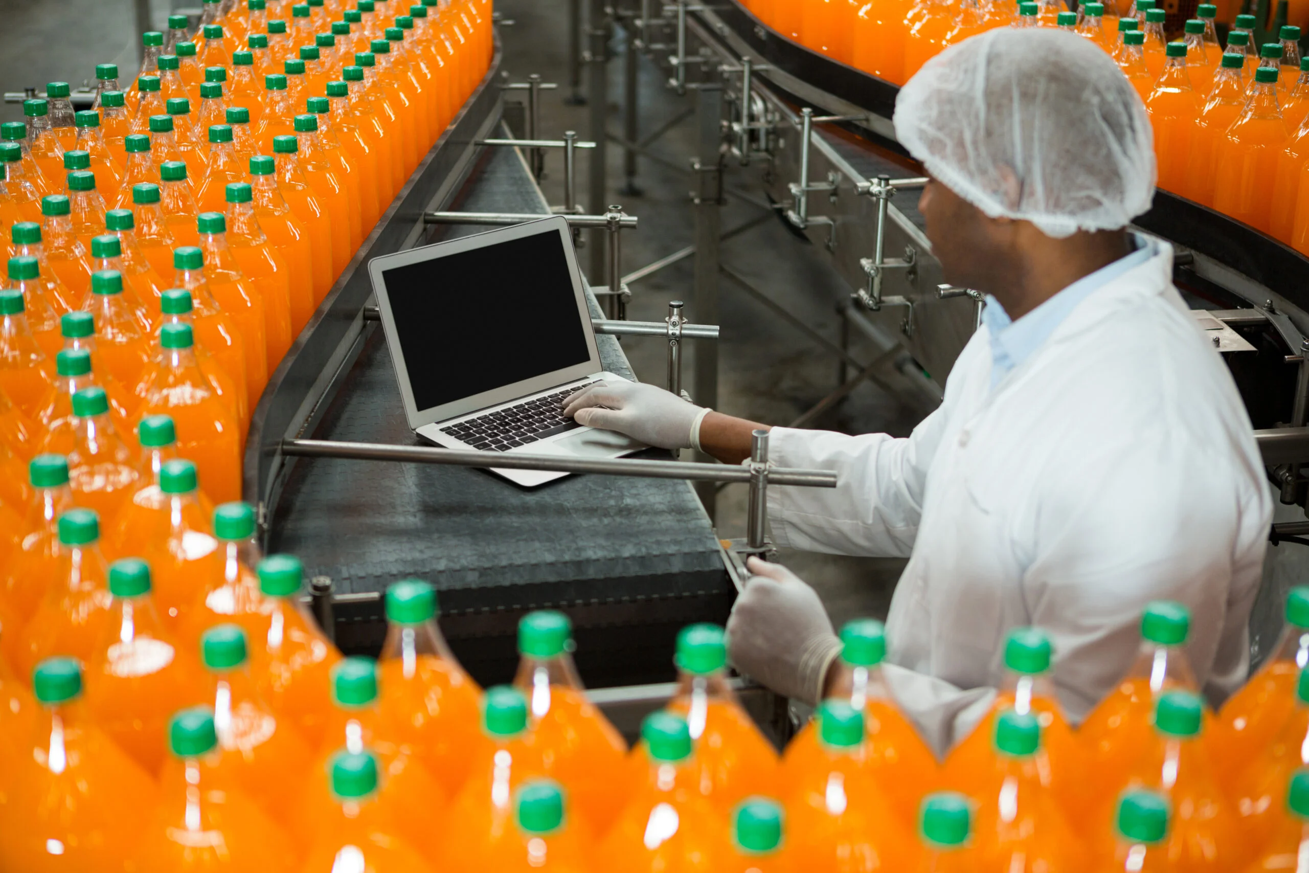 Worker using a laptop on a beverage production line