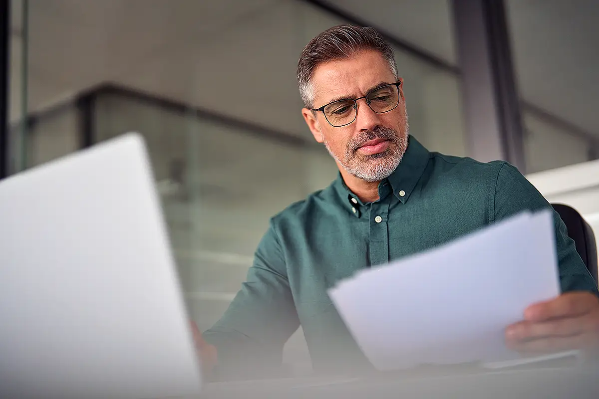 Manager reviewing documents beside a laptop